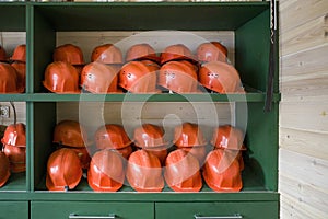 wooden shelving with orange protective helmets. the concept of workplace safety