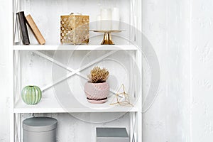 Wooden shelving unit with decor near grey wall. Bookcase with photo frame mockup and candles, living room interior details