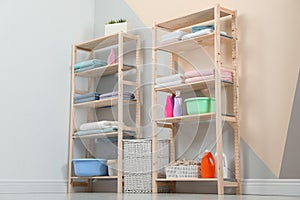 Wooden shelving units with clean towels and detergents in stylish room