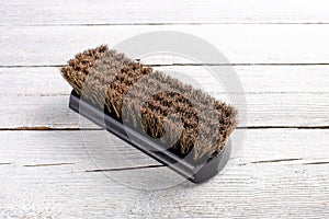 Wooden shoe shine polish brush over white wooden background