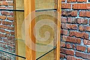 Wooden showcase with glass shelves on a brick wall background