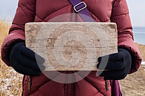 Wooden sign or board in female hands as a layout for the message text