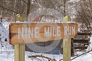 A wooden sign engraved with Nine Mile Run, a stream in Frick Park, an urban park in Pittsburgh, Pennsylvania, USA