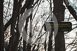 Wooden sign in the forest. Translation: Learn to laugh. Laughing from your heart is better than any medicine.