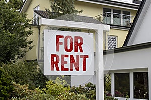 Wooden sign in front of a house with message For Rent, For Sale, and the german words for sale - zu verkaufen photo