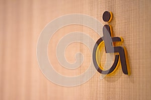 Wooden sign in front of a toilet for the disabled on a wooden background