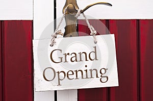 Wooden sign hanging on a door handle with message grand opening