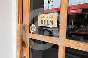 Wooden sign hangs welcome open coffee shop