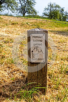 Wooden sign with inscription: Honden loslopen gebied, which means: dogs off leash area, entrance to free zone