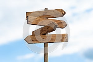 Wooden sign post isolated on blue sky with white clouds