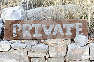 Wooden sign private on the stone wall