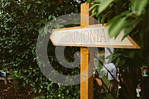 Wooden sign reading `Ceremony` in italian during wedding day celebrations. Detail of wedding decorations