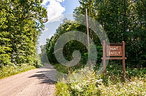 A wooden sign saying HUNT SAFELY on  the side of a dirt road in Warren county, Pennsylvania, USA