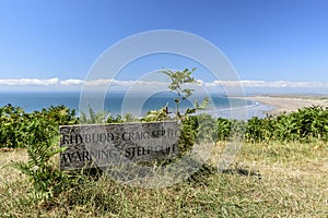 Wooden sign saying `warning Steep Cliff`.