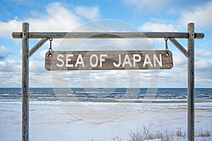 Wooden sign with sea of Japan text against sea, blue sky and beach