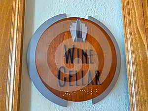 A wooden sign that states Wine Cellar outside a door of a condo building