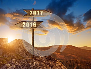 Wooden sign with text 2016 and 2017 at sunset.