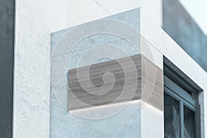 Wooden signage with copyspace and backlight on the corner of modern concrete building near entrance, 3D rendering, mockup