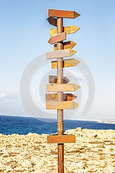 Wooden signpost on the background of the sea and blue sky on a sunny day.