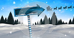 Wooden signpost in Christmas Winter landscape and Santa`s sleigh and reindeer`s