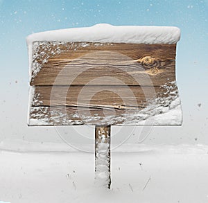 Wooden signpost with snow on it and snowfall