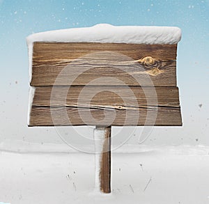 Wooden signpost with less snow on it and snowfall