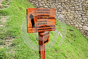 Wooden signpost to the INKA BRIDGE, GUARDHOUSE, SUN GATE and WAYNAPICCHU MOUNTAIN in the archaeological site of Machu Picchu