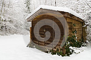 Wooden slat garden shed with snow on the ground and the roof