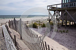 A wooden slated sand fence is partly buried in an ocean beach dune.