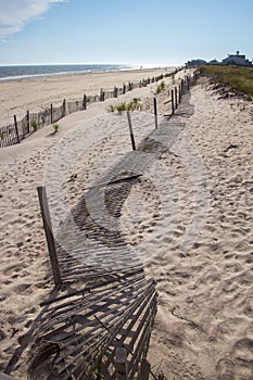 A wooden slated sand fence is partly buried in an ocean beach dune.