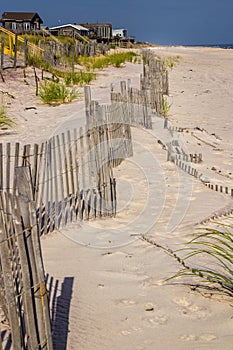 A wooden slated sand fence is partly buried in an ocean beach dune.