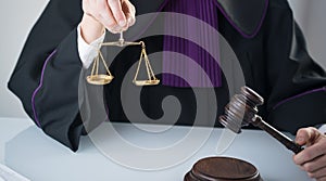 Wooden sledge gavel on a modern table. Modern law office. Books and laptop in the background.