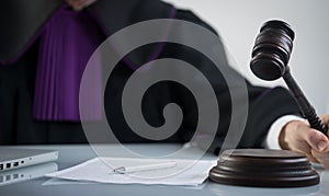 Wooden sledge gavel on a modern table. Modern law office. Books and laptop in the background.