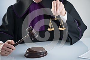 Wooden sledge gavel on a modern table. Modern law office. Books and laptop in the background.