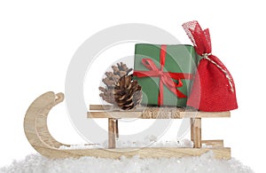 Wooden sleigh with Christmas gifts, pine cone and artificial snow on white background