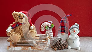 Wooden sleigh with teddy bear, snowman, pixy, candy cane and pine cones photo