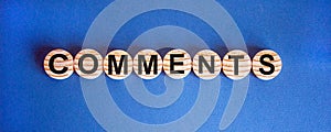 Wooden small circles with word `comments` on blue background. Concept image. Copy space