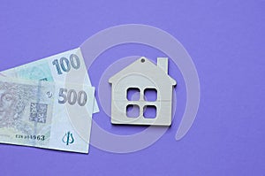 wooden small decorative house and paper money on purple background, sale