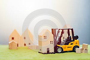 Wooden small home model with forklift car for moving house or home building renovation for good community concept