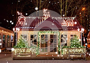 Wooden small house with New Year decoration in the night. Christmas background. Christmas window. Christmas tree outside