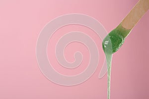 Wooden spatula with hot depilatory wax on pink background. Space for text