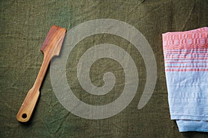 The wooden spatula lie on a green ragcloth next to the napkin