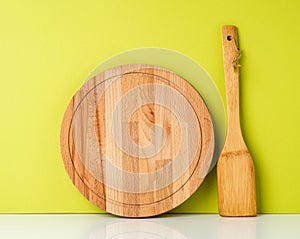 Wooden spatula and wooden round cutting Board, on a white table