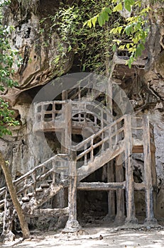 A wooden spiral staircase leading to a cave in a forest in Thailand