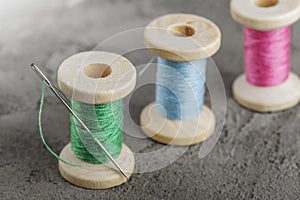 wooden spools with colored threads and a sharp needle