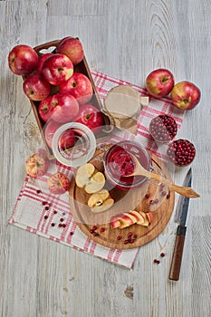 Wooden spoon with appetizing lingonberry and apple jam, jar of jam, fresh fruits and berries on light wooden table. Home canning