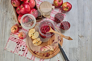 Wooden spoon with appetizing lingonberry and apple jam, jar of jam, fresh fruits and berries on light wooden table. Home canning
