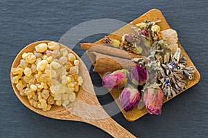 Wooden spoon of aromatic yellow resin gum next to dried flowers photo