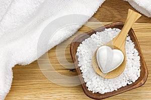 Wooden spoon in bowl filled with bath salt and towel photo