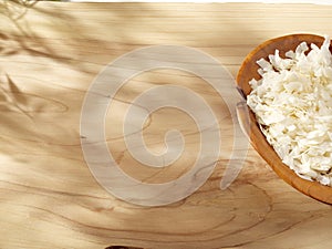 A wooden spoon with coconut chips on a sunny wooden background